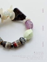 Night Garden agate and shell flower bracelet styled in a dark botanical setting